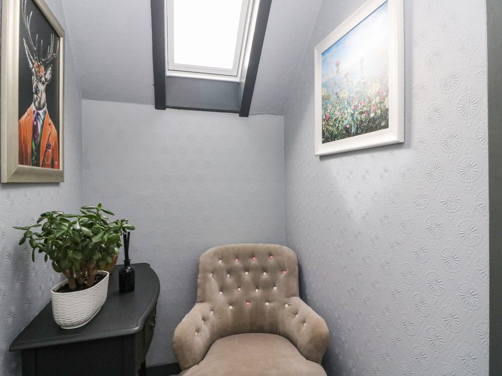 A corner with paintings, a plant, and an armchair at 3 Linshader in Stornoway