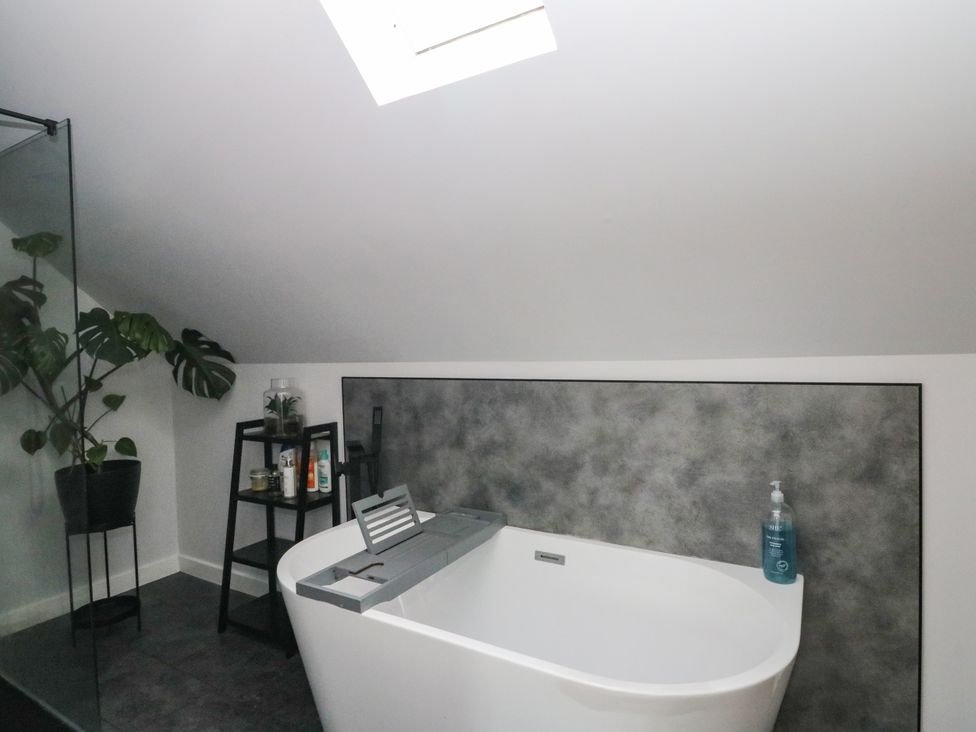 A bathroom with a bathtub, plant and shelf at 3 Linshader in Stornoway