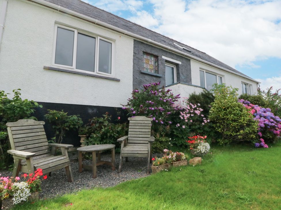 A garden with wooden chairs and table at 3 Linshader Stornoway