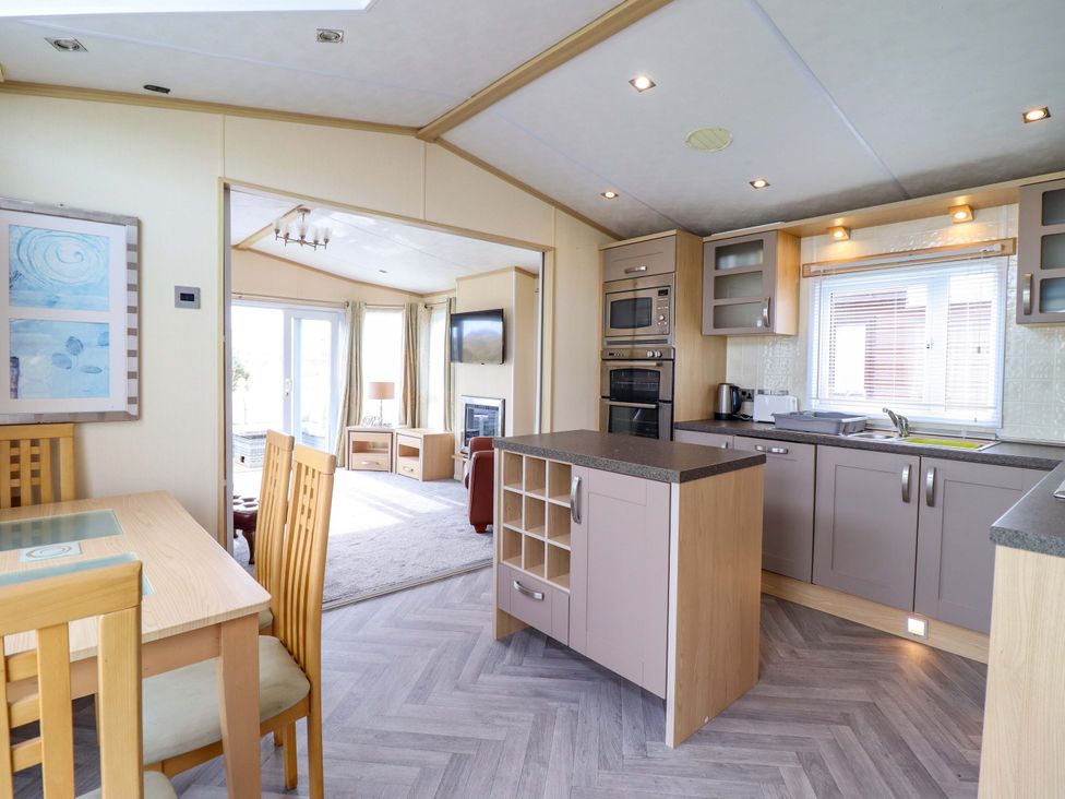 A kitchen with a dining table and appliances at Pemberton Knightsbridge in Morfa Bychan