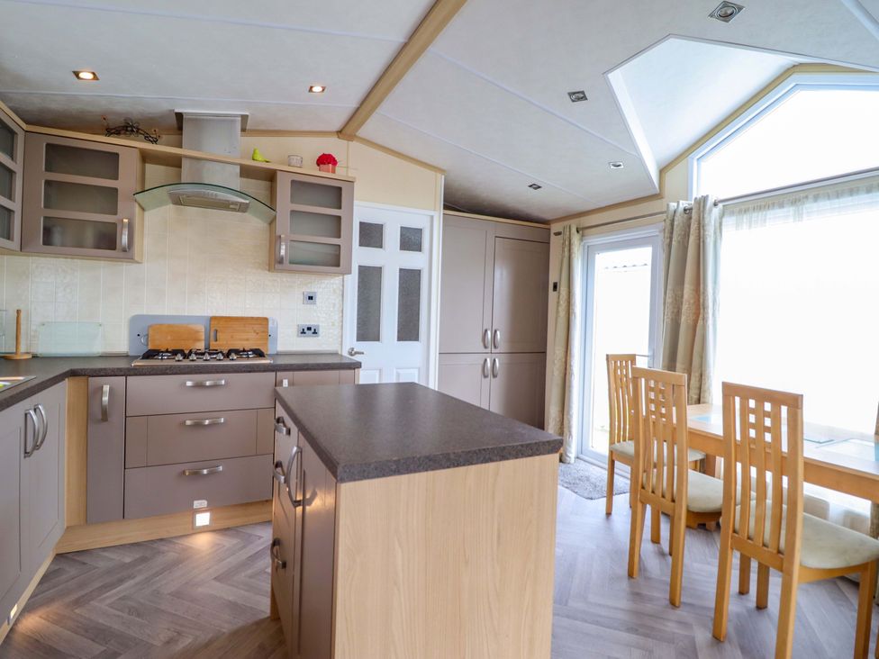 A kitchen with cabinets and dining area at Pemberton Knightsbridge in Morfa Bychan