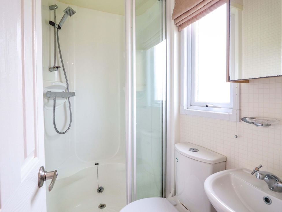 A bathroom with a shower, toilet, and sink at Pemberton Knightsbridge, Morfa Bychan