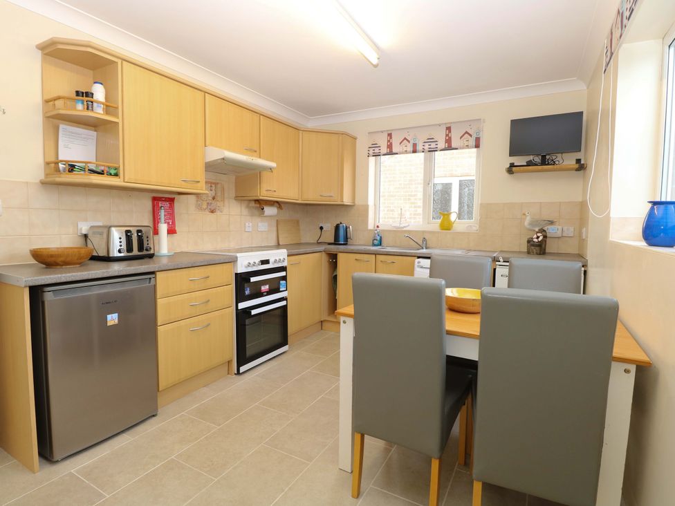 A kitchen with cabinets, stove, and dining table at The Bungalow