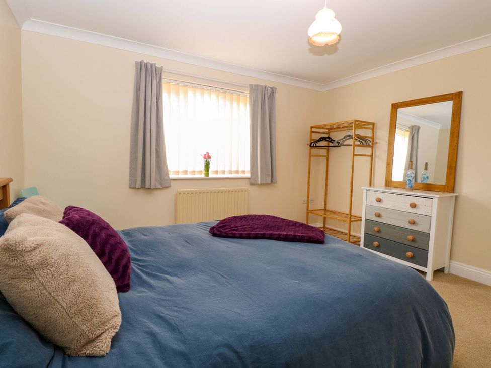A bedroom with a bed, dress rack, and mirror at The Bungalow