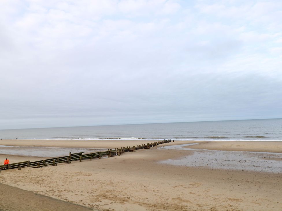 A beach with a pier and distant figures walking at The Bungalow in 