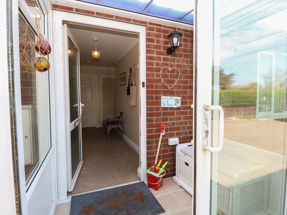 An entrance hall with a door and welcome mat at The Bungalow in Walcott