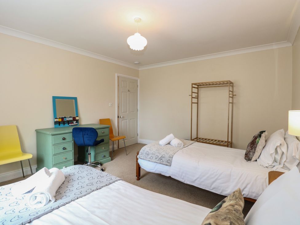 A bedroom with two beds, a chair, and a dresser at The Bungalow in Walcott