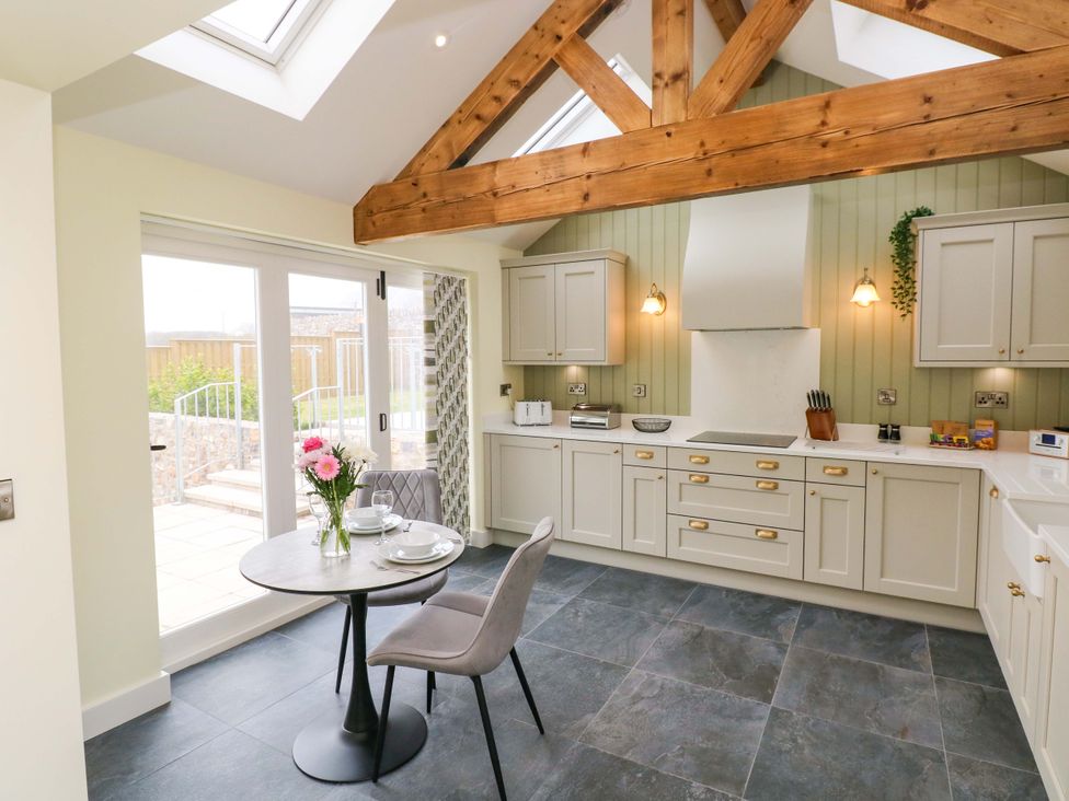 A kitchen with a table and chairs at Dairy Cottage in Oxwich