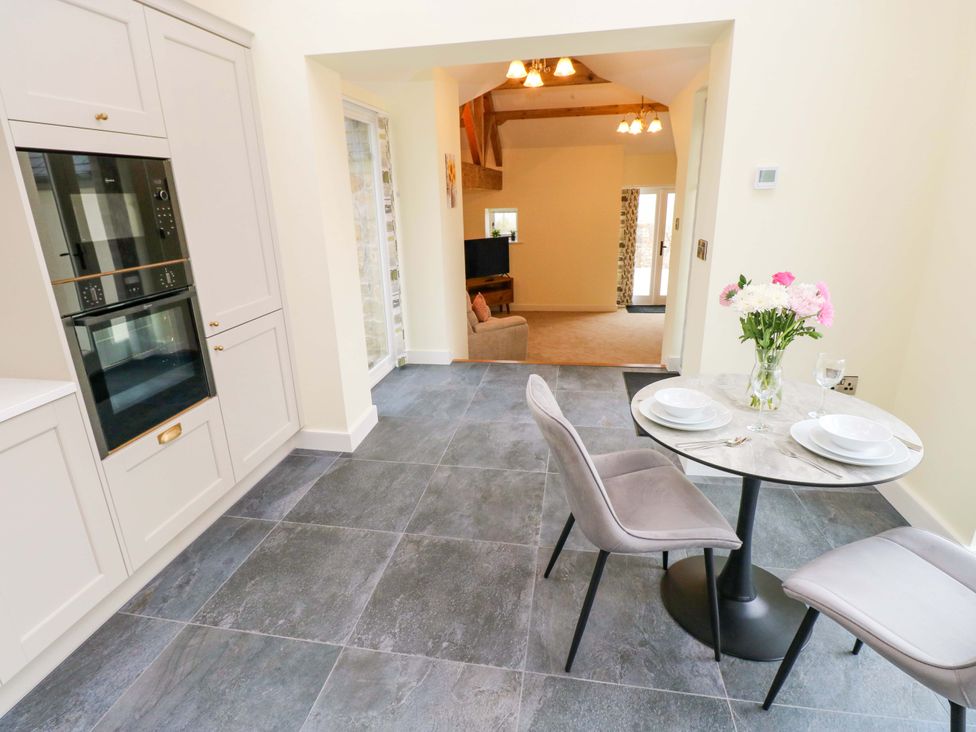A kitchen with a table and chairs at Dairy Cottage in Oxwich