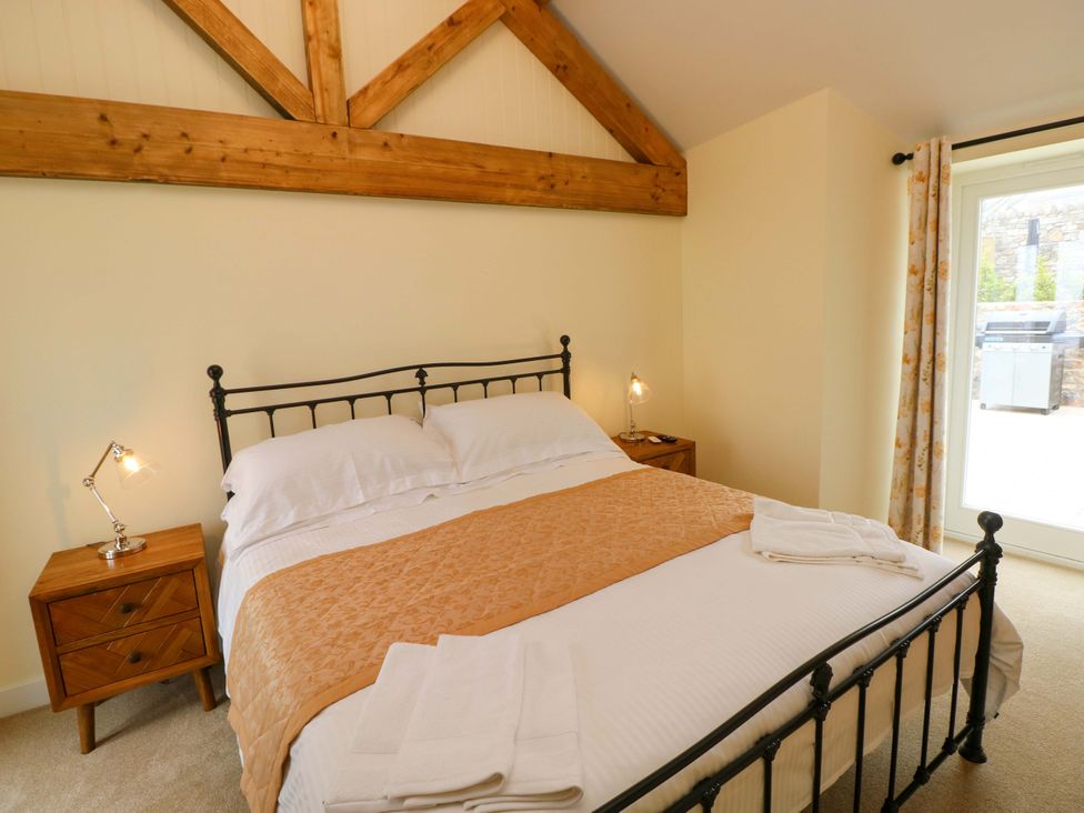 A bedroom with a bed and bedside table at Dairy Cottage in Oxwich
