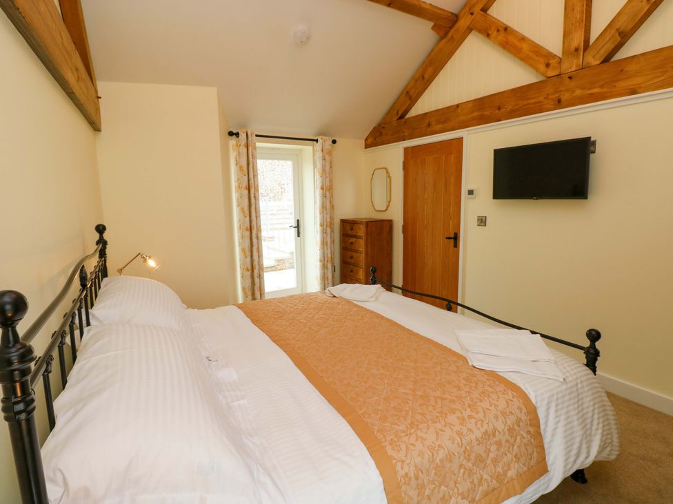 A bedroom with a bed and dressing table at Dairy Cottage in Oxwich