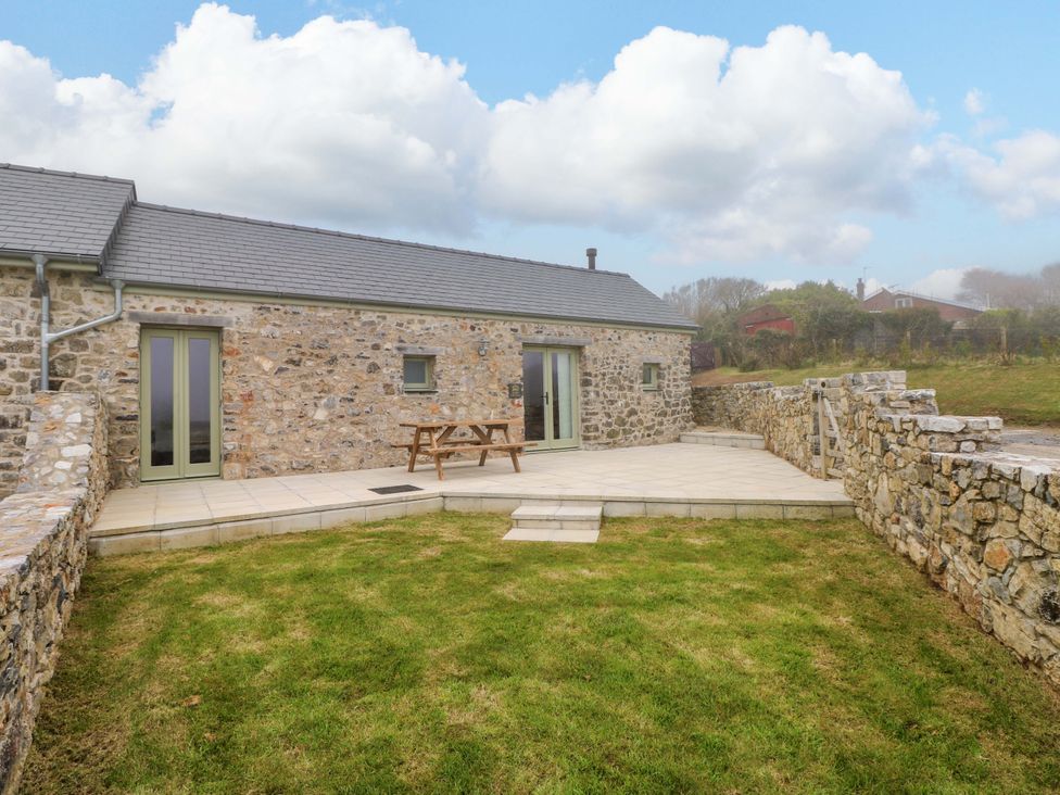 A stone house with a patio and table at Dairy Cottage in Oxwich