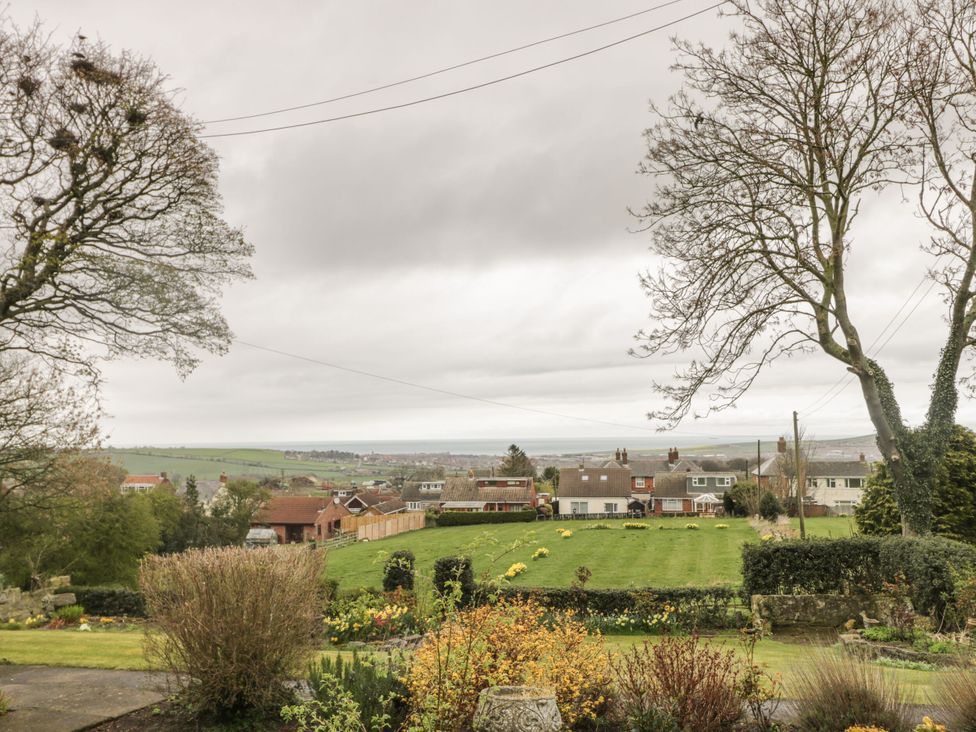 A view of houses and garden with trees in the foreground at The Calf House in Lingdale near Saltburn-by-the-Sea