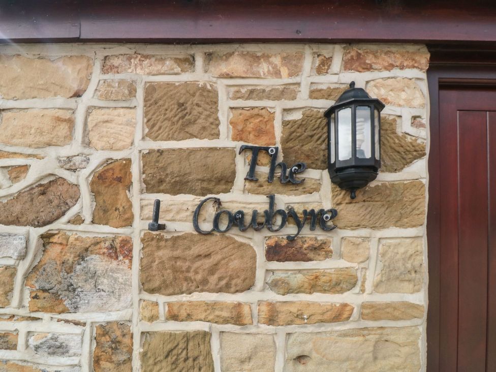 A stone wall with a light and sign at The Cow Byre Lingdale