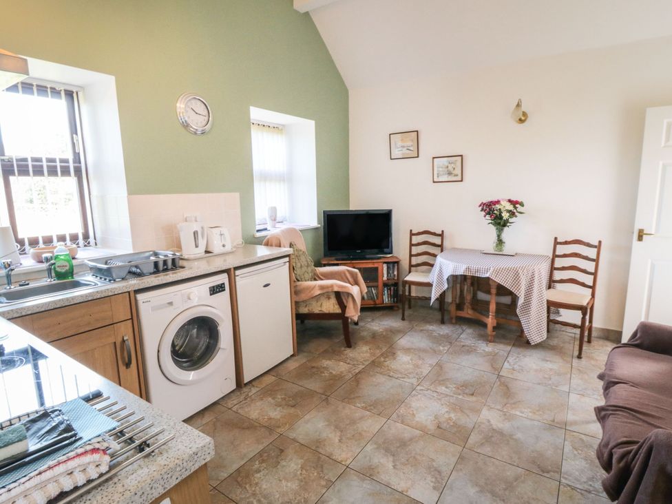 A kitchen with a washing machine and table at The Cow Byre in Lingdale