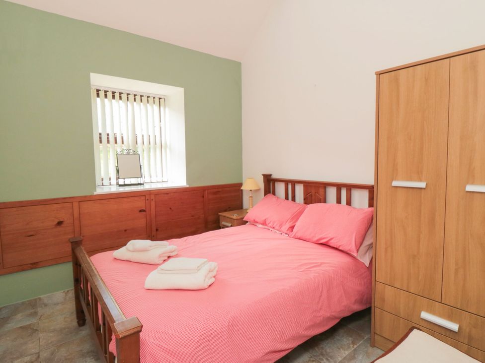 A bedroom with a bed and wardrobe at The Cow Byre in Lingdale