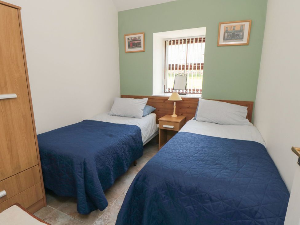 A bedroom with two beds and a nightstand at The Cow Byre in Lingdale