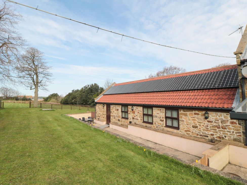 An outdoor view of a building with grass and trees at The Cow Byre in Lingdale