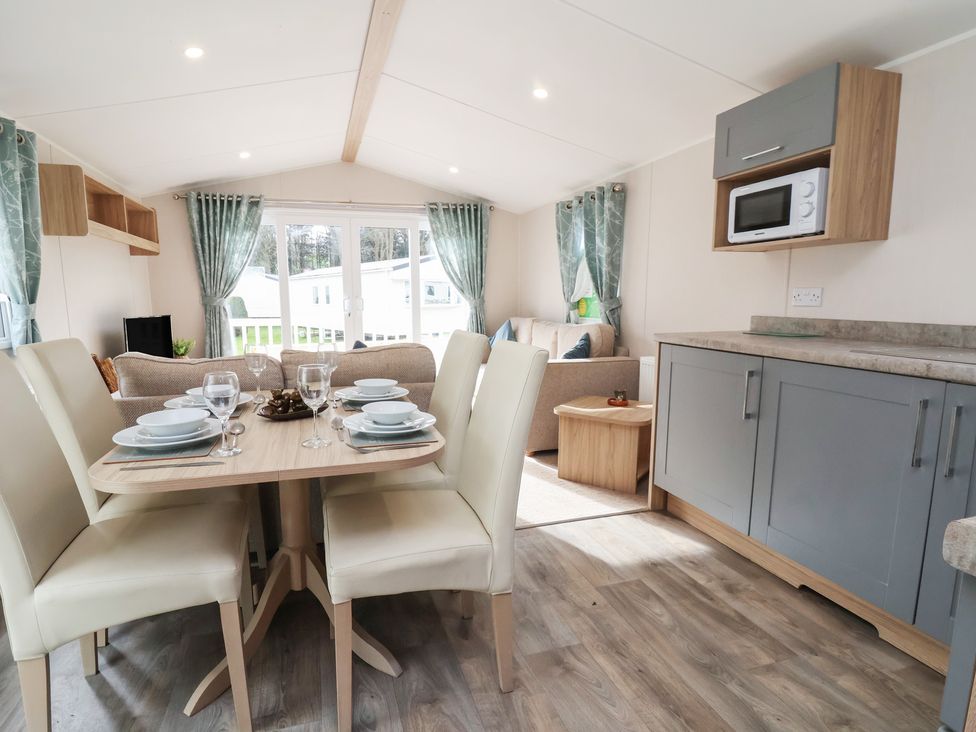 A lounge with a dining area and kitchen cabinets at Willerby Malton 176 in Ruthin