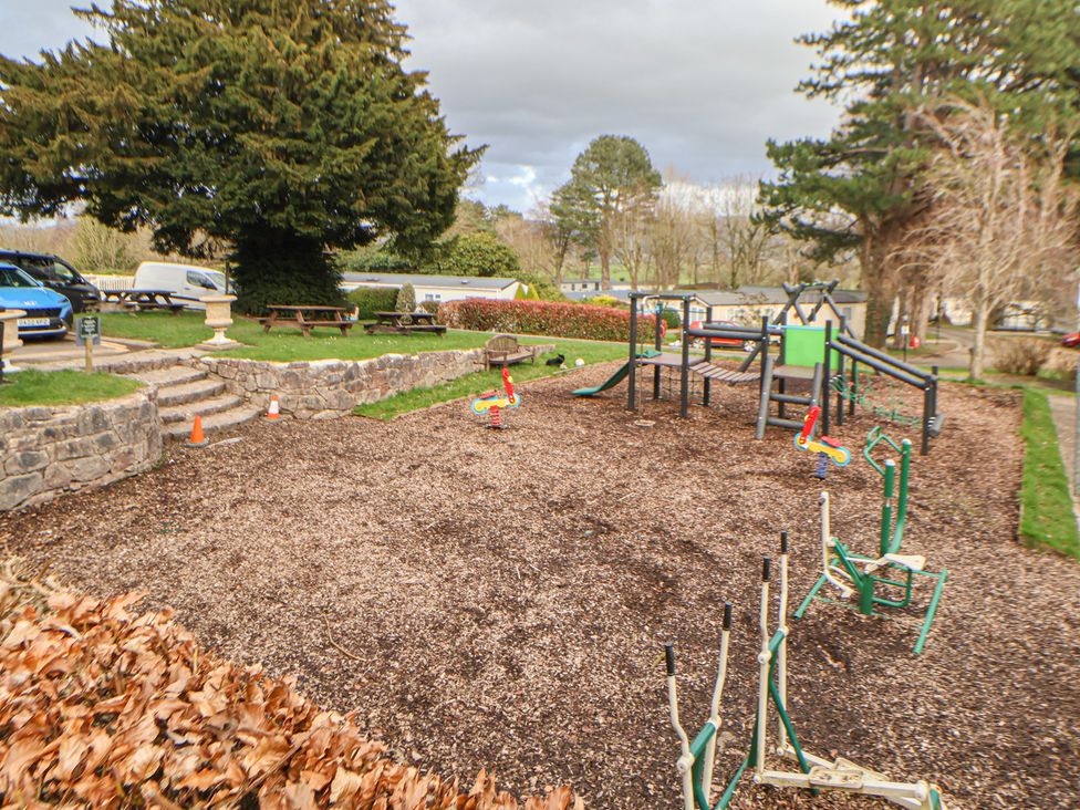 A playground area with equipment and seating at Willerby Malton 176 in Ruthin