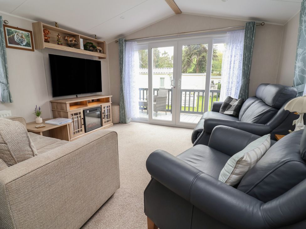 A living room with a television and sliding doors at Willerby Malton in Ruthin
