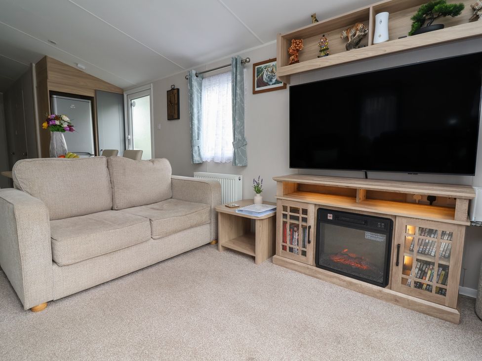 A living room with a sofa, television, and coffee table at Willerby Malton in Ruthin
