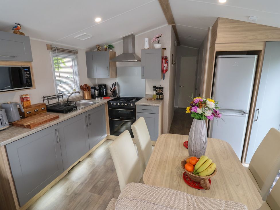 A kitchen with a dining table and appliances at Willerby Malton in Ruthin