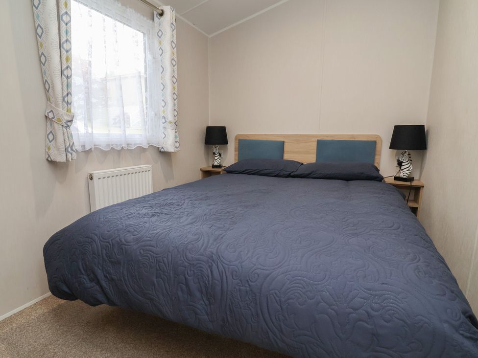 A bedroom with a bed and nightstands at Willerby Malton in Ruthin