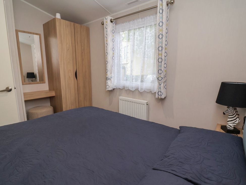 A bedroom with a bed and mirror at Willerby Malton in Ruthin