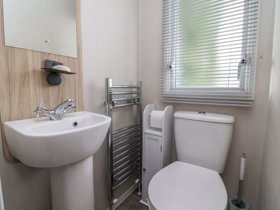 A bathroom with a sink, toilet, and towel rack at Willerby Malton in Ruthin