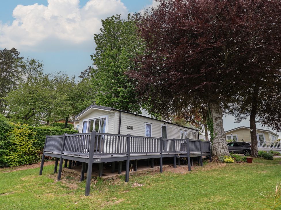 A mobile home with a deck and trees at Willerby Malton in Ruthin