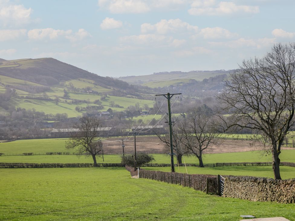 An outdoor landscape with fields, electric poles, and hills at Thorn Tree Cottage in Hope Valley