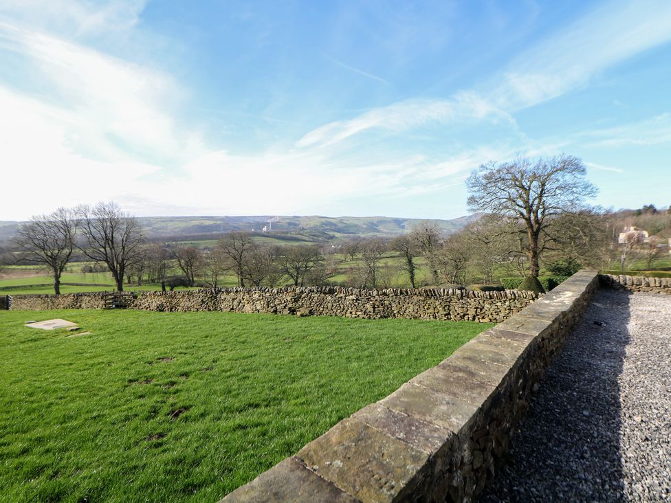 A landscape view featuring grass, trees, and a stone wall at Thorn Tree Cottage in Hope Valley