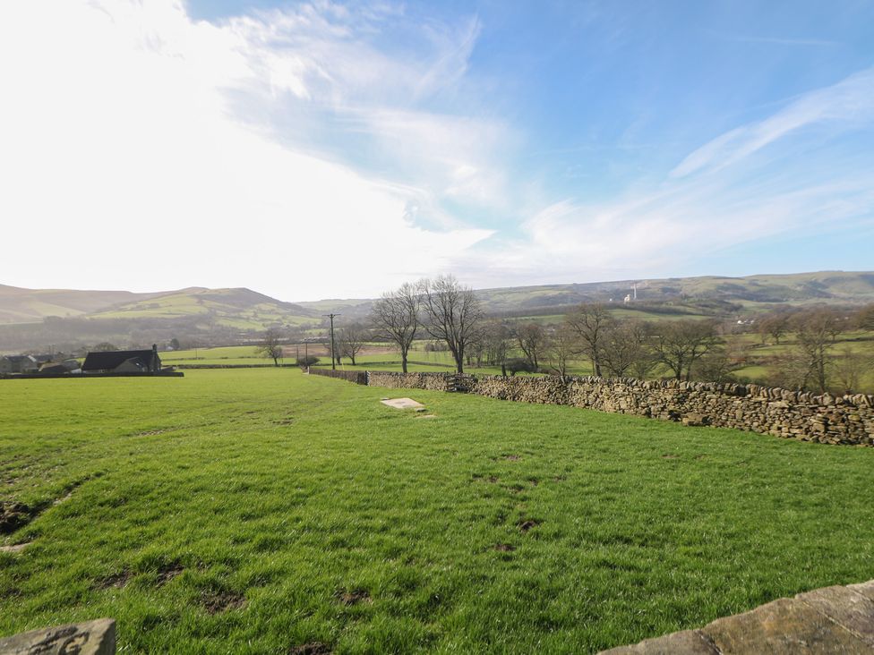 An outdoor view of a grassy field with trees and mountains at Thorn Tree Cottage Hope Valley