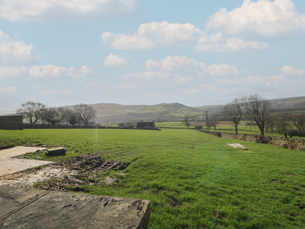 A grassy field with hills and trees at Thorn Tree Cottage Hope Valley