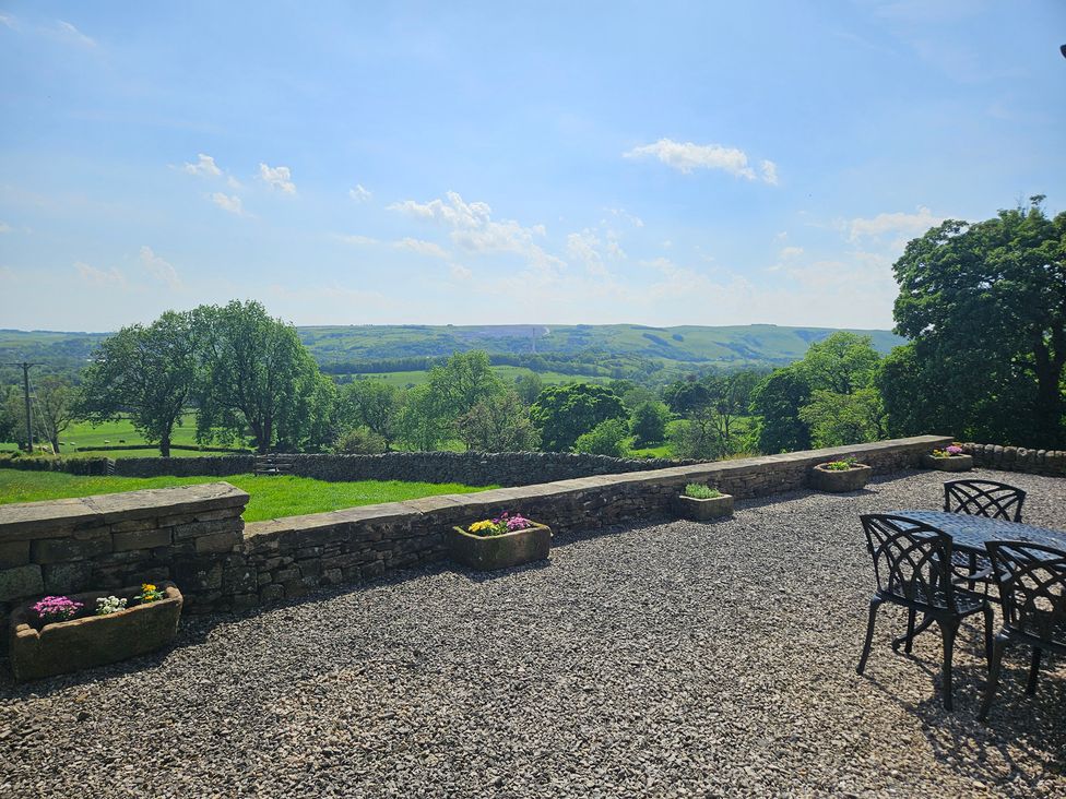 An outdoor area with a table and chairs overlooking hills at Thorn Tree Cottage in Aston near Hope