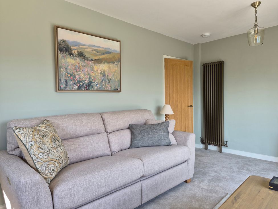 A living room with a sofa and a painting at Thorn Tree Cottage in Aston near Hope