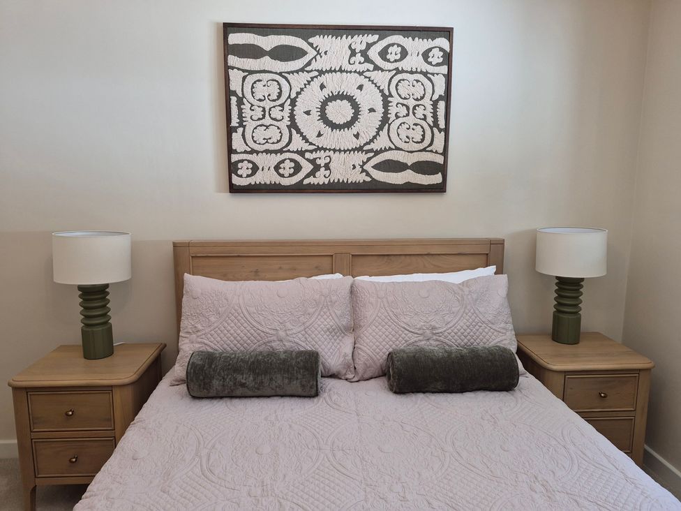 A bedroom with a bed, bedside tables, and wall art at Thorn Tree Cottage in Aston near Hope