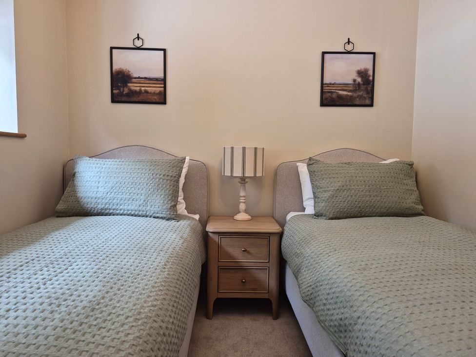 A bedroom with two beds and a bedside table at Thorn Tree Cottage Aston near Hope