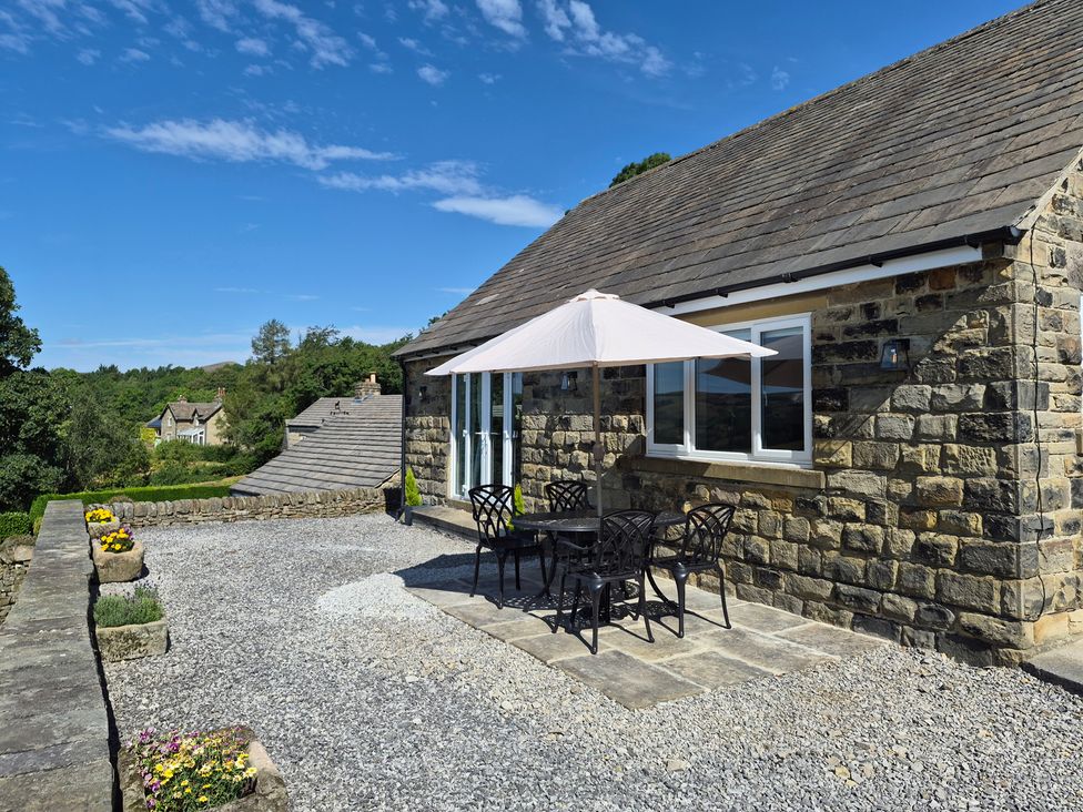 An outdoor area with a table and chairs under a parasol at Thorn Tree Cottage in Aston near Hope
