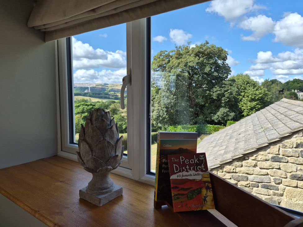 A window with a view and books on a ledge at Thorn Tree Cottage in Aston near Hope