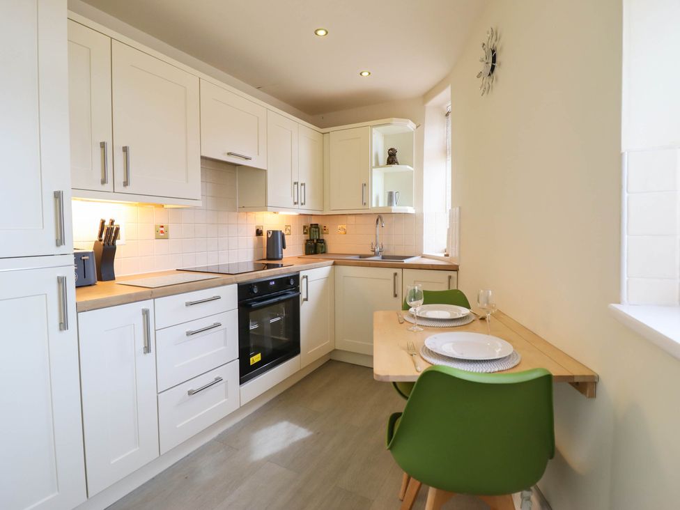 A kitchen with cabinets and a dining table at Harbour Cottage in Barmouth