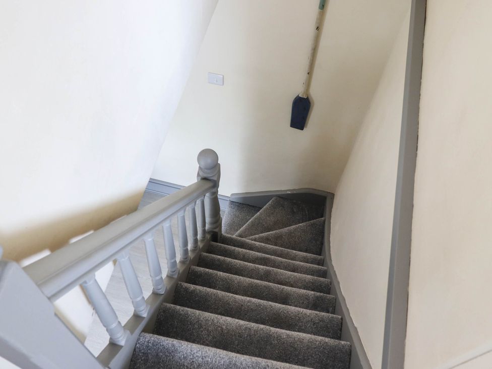 A staircase with a handrail and a shovel at Harbour Cottage in Barmouth