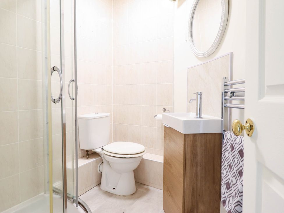 A bathroom with a shower, toilet and sink at Harbour Cottage Barmouth