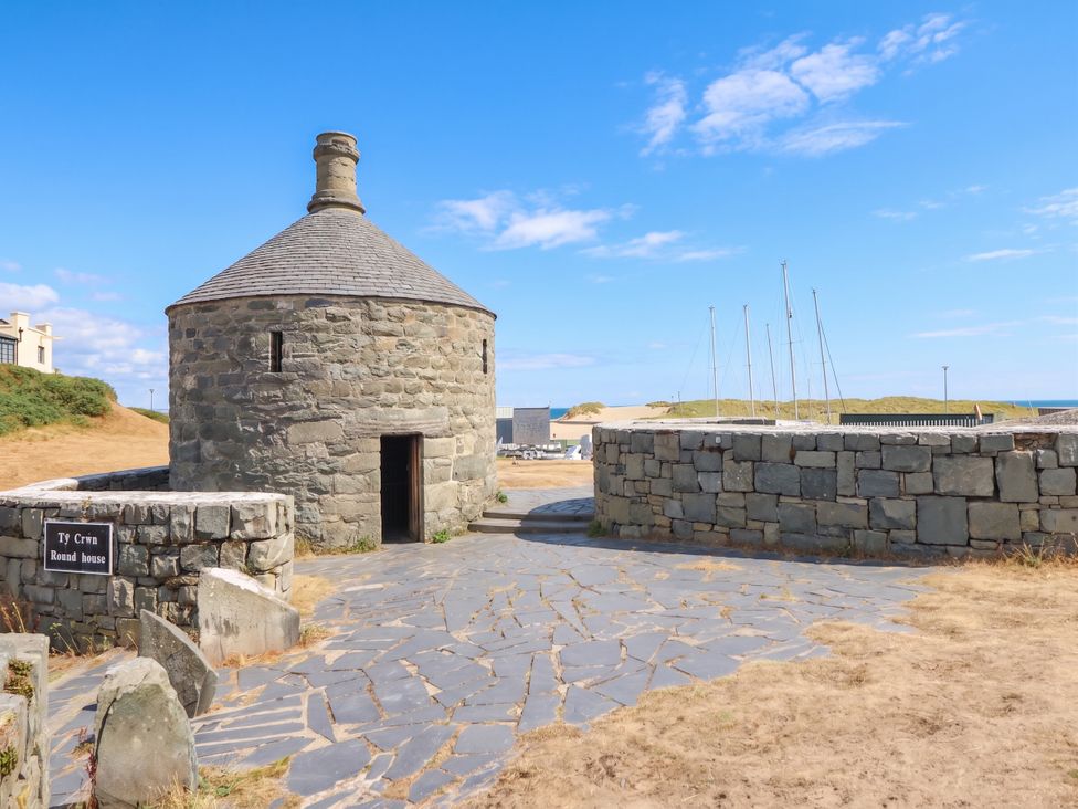 A round house with a stone wall and pathway at Ty Crwn in Barmouth