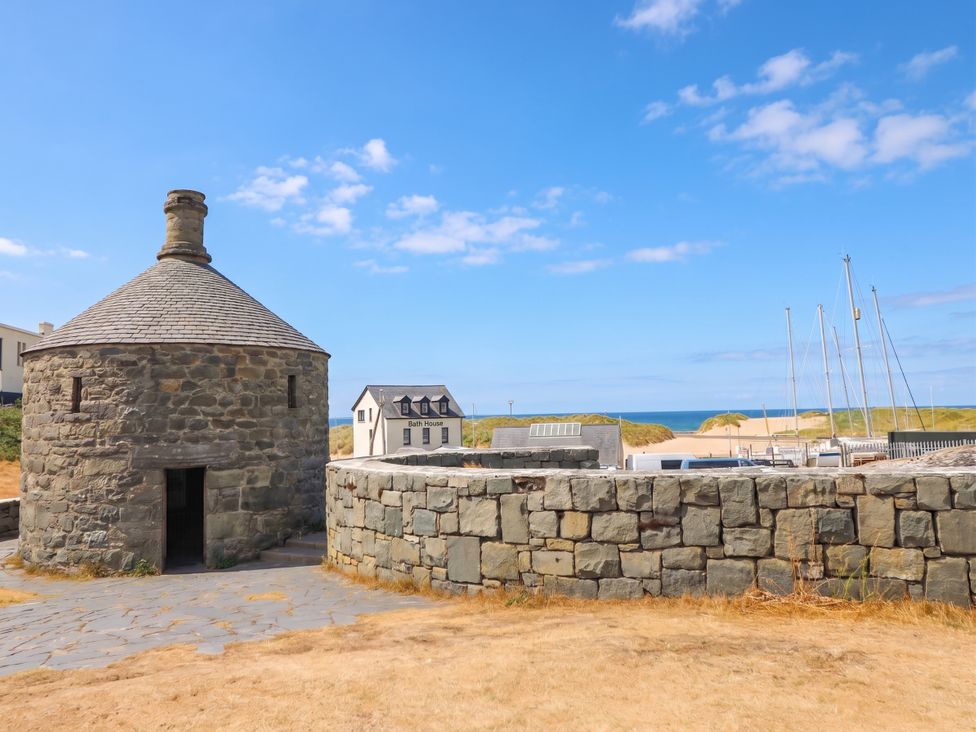 A stone building with boats in the background at Harbour Cottage in Barmouth