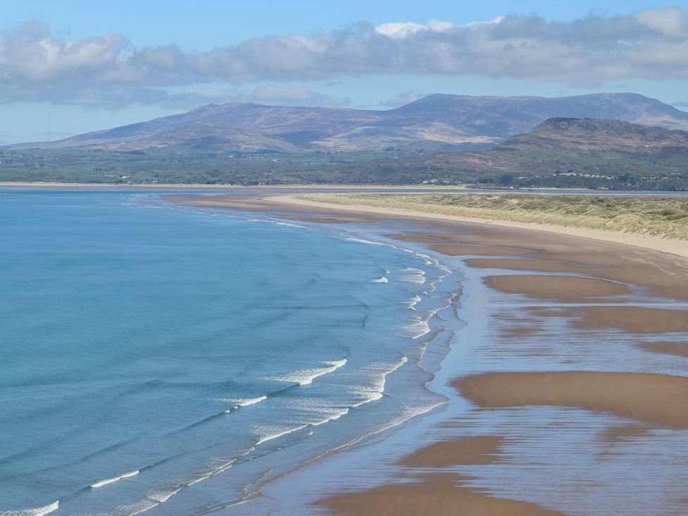 A beach with waves and mountains in the background at Harbour Cottage Barmouth