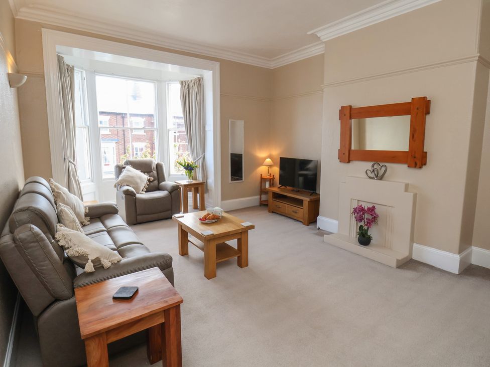 A living room with a sofa, armchair, coffee table and television at Time Out in Whitby