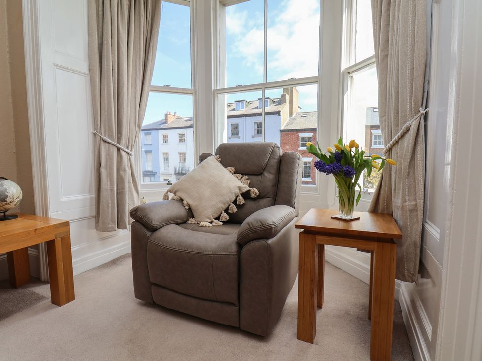 A living room with an armchair and flower vase at Time Out in Whitby