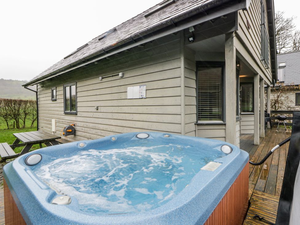An outdoor area with a hot tub and seating at Maple Lodge in Knighton